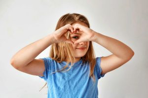 i_close-up-beautiful-blonde-girl-making-heart-with-hands-looking-through-it-posing-photo-with-smile-happy-expression